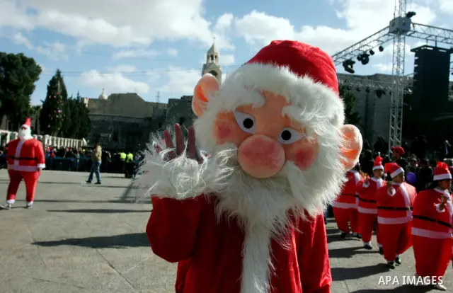 A person dressed as Santa Claus rings a bell during celebrations for Christmas near the Church of the Nativity in West Bank town of Bethlehem December 24, 2011. Photo by Issam Rimawi