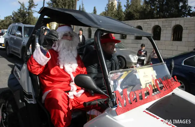 A man dressed as Father Christmas drives past the Israeli built separation barrier as Christians arrive to celebrate Christmas mass in the West Bank city of Bethlehem, on December 24, 2011. Photo by Issam Rimawi