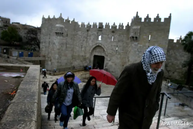 Palestinians walk outside Damascus Gate leading into the old city of Jerusalem from their way from prayer in the Al-Aqsa Mosque compound, Islam's third holiest site, on Dec 25, 2011. Photo by Mahfouz Abu Turk