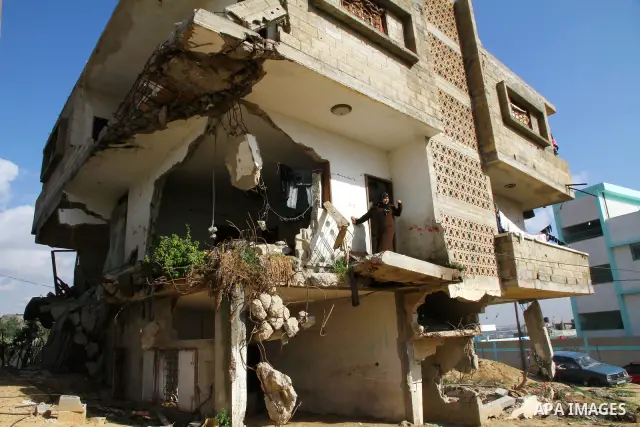 Palestinian woman stands in her house destroyed during the three-week offensive Israel launched before three years, in Gaza City, on 26 December 2011. which was damaged during Israel's three-week offensive three years ag...