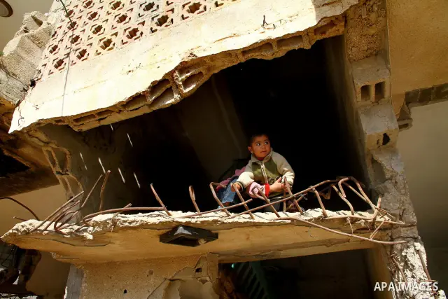 Palestinian woman stands in her house destroyed during the three-week offensive Israel launched before three years, in Gaza City, on 26 December 2011. which was damaged during Israel's three-week offensive three years ag...