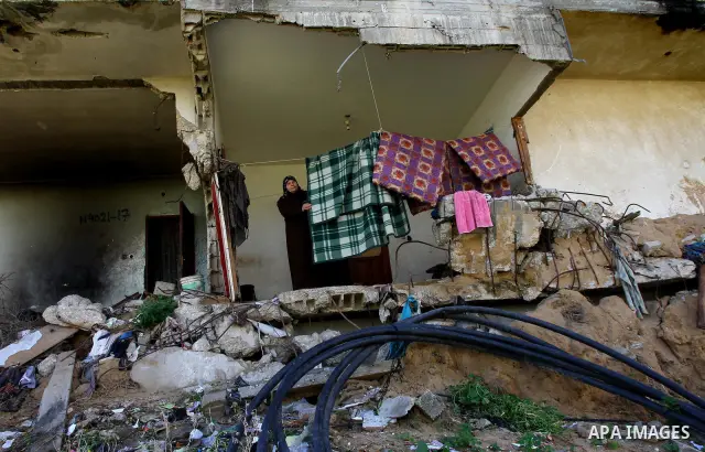 Palestinian woman stands in her house destroyed during the three-week offensive Israel launched before three years, in Gaza City, on 26 December 2011. which was damaged during Israel's three-week offensive three years ag...