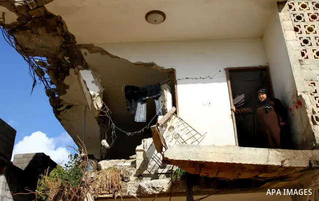 Palestinian woman stands in her house destroyed during the three-week offensive Israel launched before three years, in Gaza City, on 26 December 2011. which was damaged during Israel's three-week offensive three years ag...
