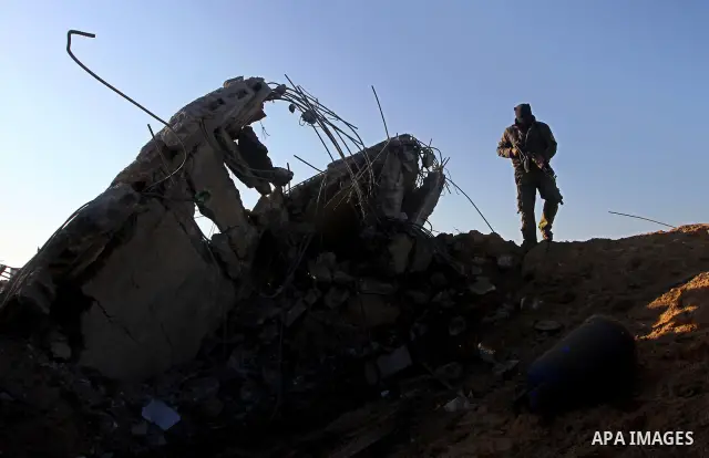 A masked Palestinian Islamic Jihad militant is seen through a tyre as he surveys the damage at a training camp after an Israeli air strike in Gaza December 29, 2011. The Israeli army confirmed that it targeted two sites...