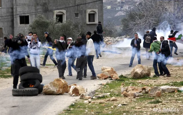 Palestinian protesters run during a protest against the Jewish settlement of Qadomem, near the West Bank City of Nablus on 30 December 2011. Seven Palestinians were wounded during the clashes, medical sources said. Photo...
