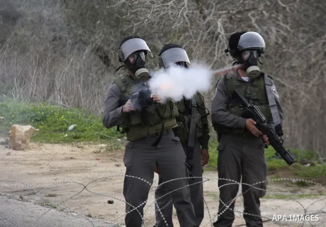 An Israeli soldier fires his weapon at Palestinian youths during a protest against the Jewish settlement of Qadomem, near the West Bank City of Nablus on 30 December 2011. Seven Palestinians were wounded during the clash...