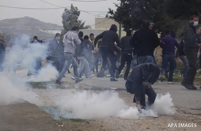 Palestinian protesters run during a protest against the Jewish settlement of Qadomem, near the West Bank City of Nablus on 30 December 2011. Seven Palestinians were wounded during the clashes, medical sources said. Photo...