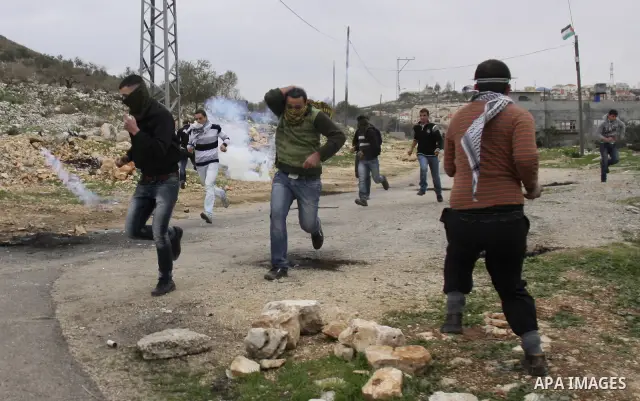 Palestinian protesters run during a protest against the Jewish settlement of Qadomem, near the West Bank City of Nablus on 30 December 2011. Seven Palestinians were wounded during the clashes, medical sources said. Photo...