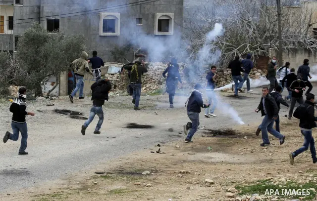 Palestinian protesters run during a protest against the Jewish settlement of Qadomem, near the West Bank City of Nablus on 30 December 2011. Seven Palestinians were wounded during the clashes, medical sources said. Photo...