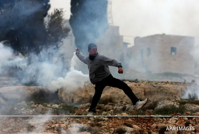 A Palestinian stone-thrower throws back a tear gas canister fired by Israeli soldiers during clashes at a weekly protest in the West Bank village ofNabi Saleh, near Ramallah December 30, 2011. Photo by Issam Rimawi