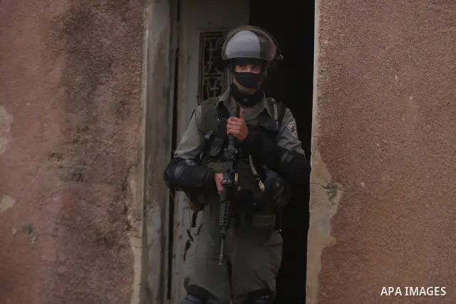 An Israeli soldier fires his weapon at Palestinian youths during demonstration against the expansion of the nearby Jewish settlement of Halamish in the West Bank village of Nabi Saleh near Ramallah, Friday, Dec. 30, 2011...