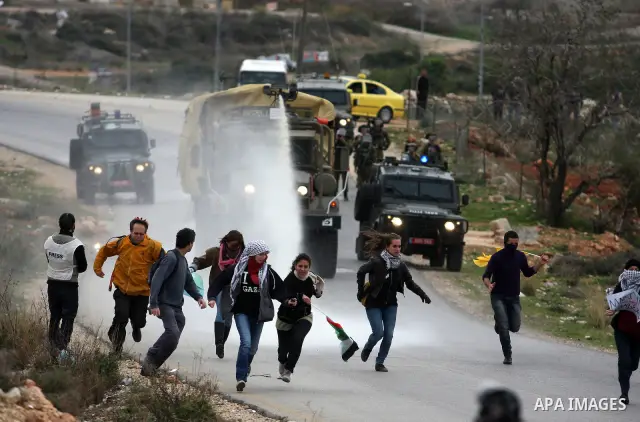 Palestinian protesters runs for cover from tear gas fired by Israeli soldiers during during demonstration against the expansion of the nearby Jewish settlement of Halamish in the West Bank village of Nabi Saleh near Rama...