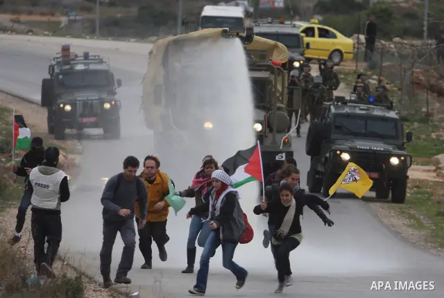 Palestinian protesters runs for cover from tear gas fired by Israeli soldiers during during demonstration against the expansion of the nearby Jewish settlement of Halamish in the West Bank village of Nabi Saleh near Rama...