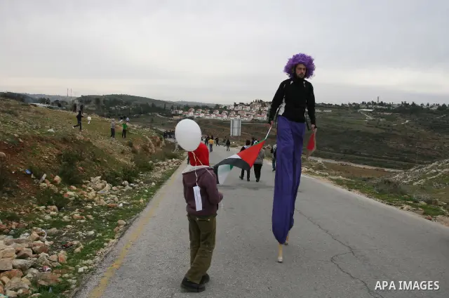 An activist walking on stilts holds a Palestinian flag during a weekly protest against a nearby Jewish settlement, in the West Bank village of Nabi Saleh, near Ramallah, December 30, 2011. Photo by Issam Rimawi