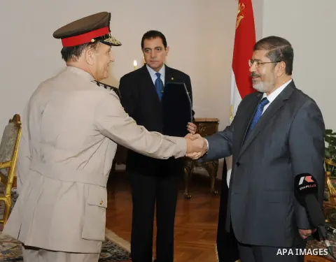 Former Armed Forces Chief of Staff Sami Anan, left, shakes hands with Egyptian President Mohammed Morsi at the Presidential Palace in Cairo, Egypt, Tuesday, Aug. 14, 2012. Egypt's president has given awards to the nation...
