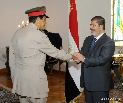Former Defense Minister Hussein Tantawi shakes hands with Egyptian President Mohammed Morsi at the Presidential Palace in Cairo, Egypt, Tuesday, Aug. 14, 2012. Egypt's president has given awards to the nation's two top m...