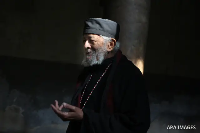 A Christian Orthodox priest stands during a mass in the Church of the Nativity, traditionally believed by Christians to be the birthplace of Jesus Christ, during the Orthodox Christmas in the West Bank city of Bethlehem,...