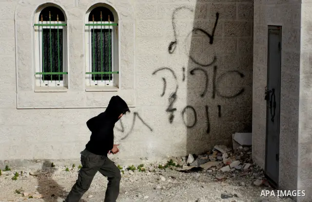 Palestinians stand outside a vandalized mosque where graffiti reading In Hebrew. was sprayed at the entrance of the mosque , in the West Bank Village of Der Stia near Nablus, Jan. 11, 2012. Assailants vandalized a Palest...