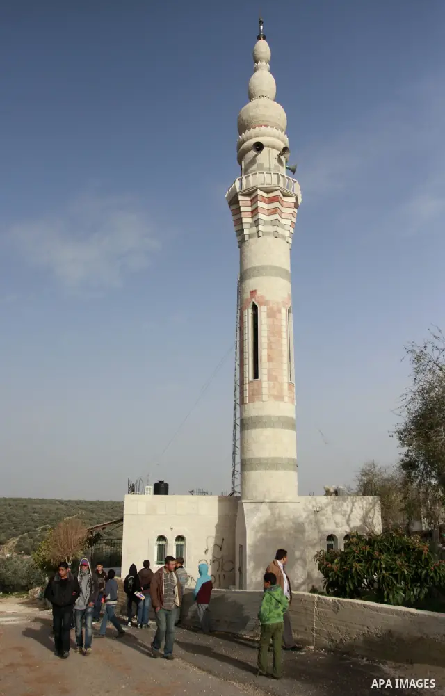 Palestinians stand outside a vandalized mosque where graffiti reading In Hebrew. was sprayed at the entrance of the mosque , in the West Bank Village of Der Stia near Nablus, Jan. 11, 2012. Assailants vandalized a Palest...