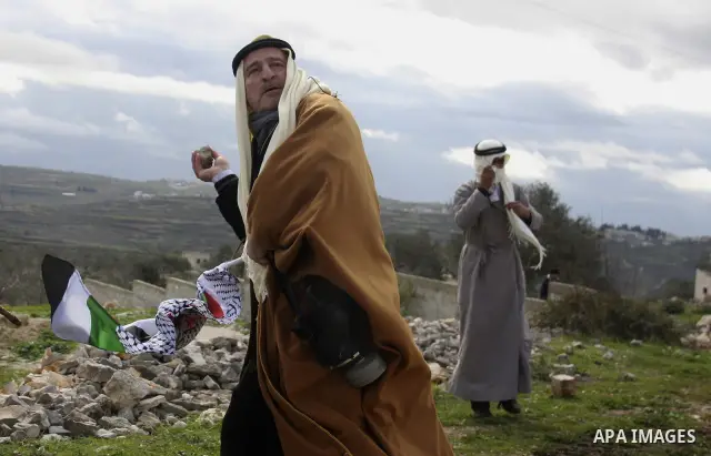 Traditionally dressed Palestinian men hurl stones at Israeli security forces during a protest in the village of Kufr Qaddum near the Israeli settlement of Kdumim, in the northern West Bank, Friday, Jan. 13, 2012. Photo b...