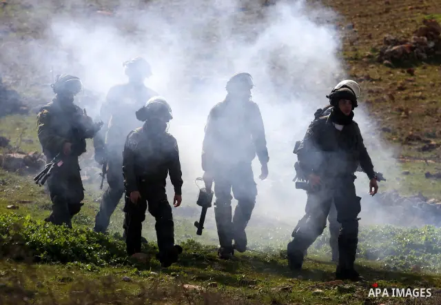 An Israeli border police officer fires a tear gas canister towards stone-throwing Palestinian demonstrators during clashes at a weekly demonstration against the construction and expansion of Israeli settlements in the We...