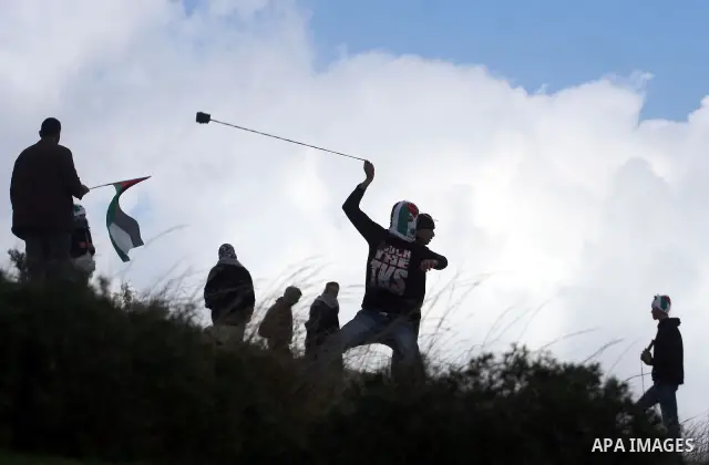 A Palestinian protester hurls stones at Israeli soldiers during a weekly demonstration against the construction and expansion of Israeli settlements in the West Bank village of Nabi Saleh, near Ramallah, on January 20, 2...