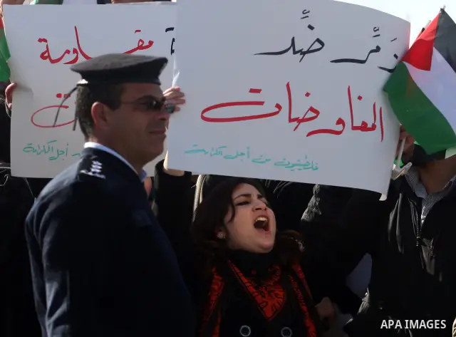 People hold Palestinian flags and placards during a protest against the peace negotiation talks between Palestinians and Israeli in front of Palestinian President Mahmoud Abbas's office in Ramallah, January 21, 2012. The...