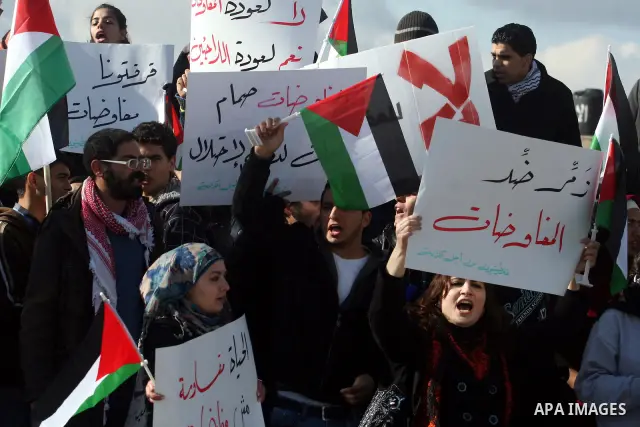 People hold Palestinian flags and placards during a protest against the peace negotiation talks between Palestinians and Israeli in front of Palestinian President Mahmoud Abbas's office in Ramallah, January 21, 2012. The...