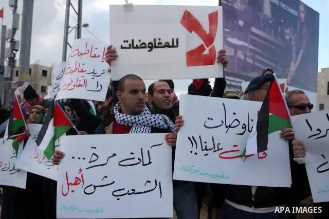 People hold Palestinian flags and placards during a protest against the peace negotiation talks between Palestinians and Israeli in front of Palestinian President Mahmoud Abbas's office in Ramallah, January 21, 2012. The...