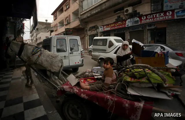 A Palestinian woman and her son use a donkey cart to collect wood and cartons for heating during cold winter days in Gaza city on Jan. 24,2012. Photo by Mahmud Nassar