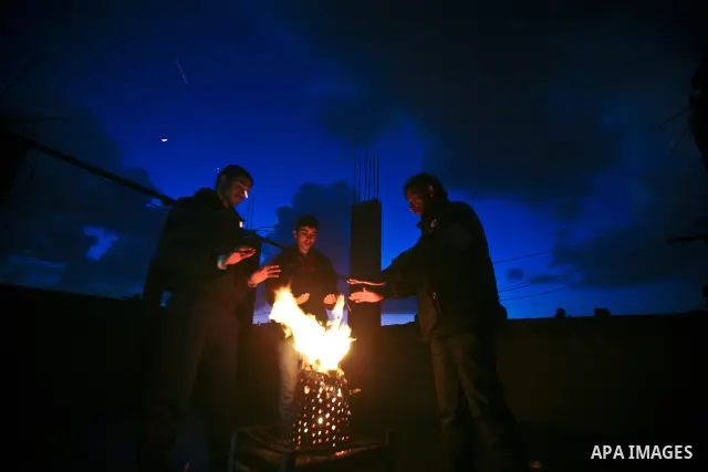 Palestinian people warm up by a fire during a cold winter night in their destroyed house, set up after the Israeli offensive on Gaza two years ago, in Jabaliya refugee camp in northren Gaza Strip on 23 January 2012. Phot...