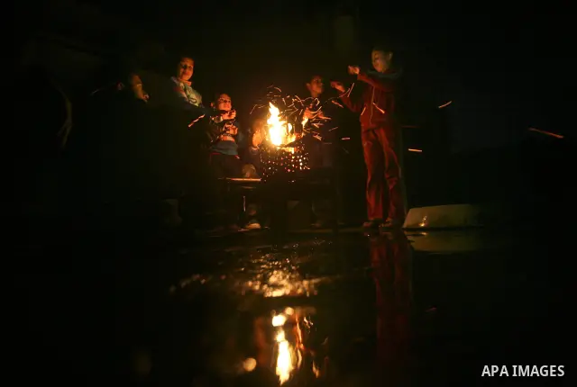 Palestinian people warm up by a fire during a cold winter night in their destroyed house, set up after the Israeli offensive on Gaza two years ago, in Jabaliya refugee camp in northren Gaza Strip on 23 January 2012. Phot...