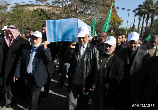 Palestinian Legislative Council members and other officials carry a mock coffin covered with the emblems of the International Committee of the Red Cross (ICRC) and the United Nations Relief and Works Agency (UNRWA) durin...
