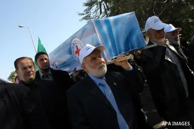 Palestinian Legislative Council members and other officials carry a mock coffin covered with the emblems of the International Committee of the Red Cross (ICRC) and the United Nations Relief and Works Agency (UNRWA) durin...