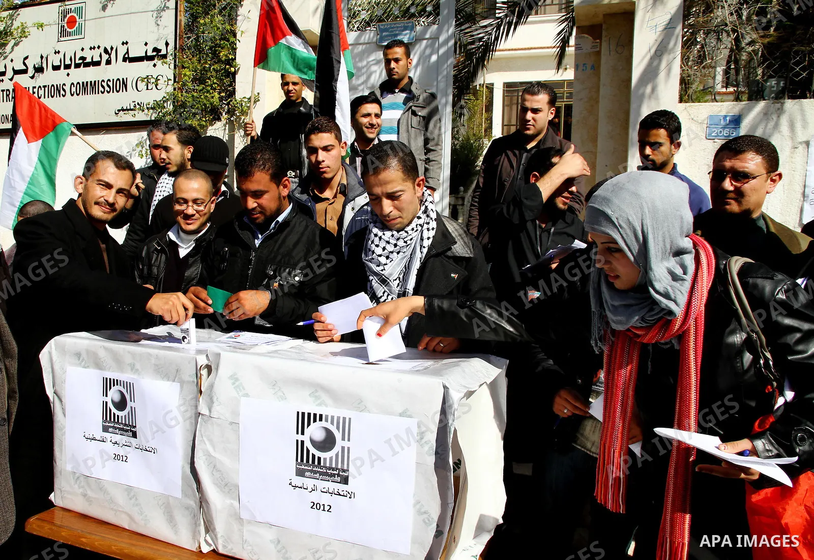 Palestinian activists wave Palestinian flags and hold election ballots during a protest calling for elections and unity between Fatah and Hamas during a demonstration in front of the recently reopened Central Elections c...