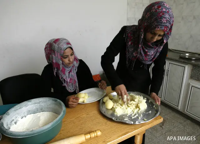 A Palestinian family prepares Bread traditional from Potatoes, at their house in town of Khan Yunis, southern Gaza Strip on February 2, 2012. Palestinian families used some of the manufacture of potato bread instead of t...