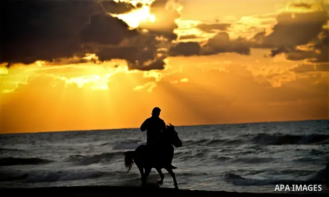 A Palestinian man is silhouetted against the setting sun as he rides a horses on a beach near Gaza City on a cold winter day's evening, on Feb. 02, 2012. Photo by Ali Jadallah