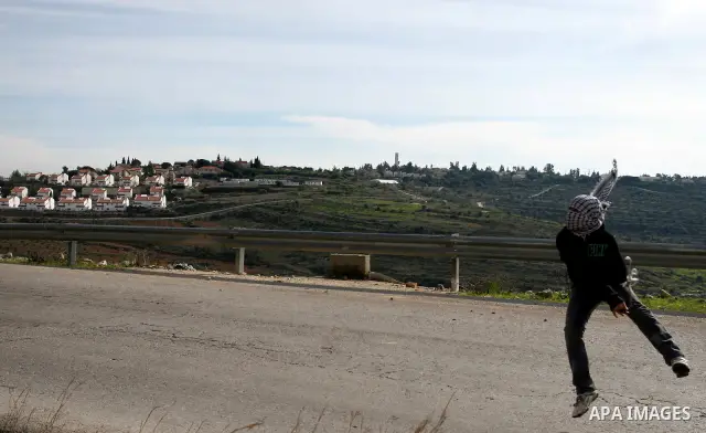 A Palestinian youth hurls stones at Israeli troops during a weekly protest against the construction of Israel's controversial separation barrier and the expansion of Jewish settlements in the West Bank village of Nabi Sa...