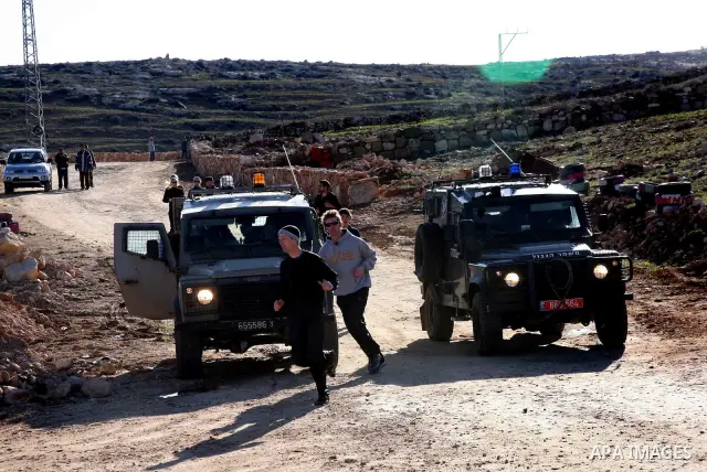 Israeli soldiers block the road in front of Palestinians, Israeli and foreign activists during a marathon to support the farmers and land owners in the West Bank city of Hebron on Feb. 4,2012. Israeli troops detained a P...