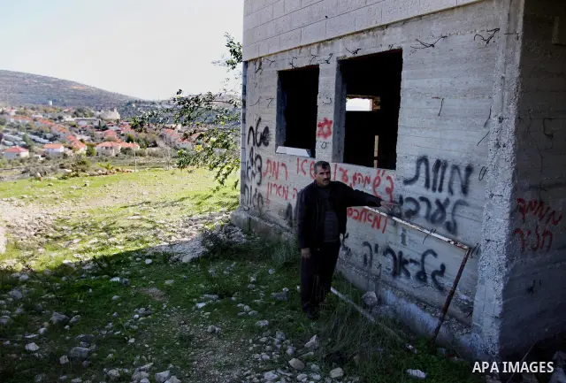 Palestinians look at graffiti sprayed on his house in the West Bank village of El-Jinya near Ramallah, Sunday, Feb. 5, 2012. Palestinians say extremist Jews have scrawled their home in a West Bank village with offensive...