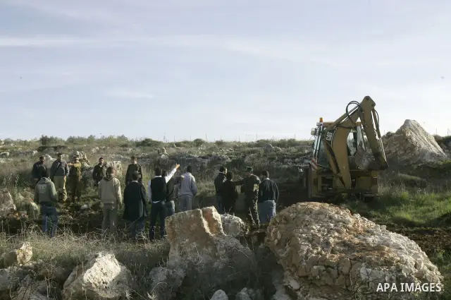 Israeli soldiers stand guards as a bulldozer of the Civil Administration during a demolition in the village of Kufr Qaddum near the Israeli settlement of Kdumim, in the northern West Bank, Sunday, Feb , 05, 2012. Photo b...