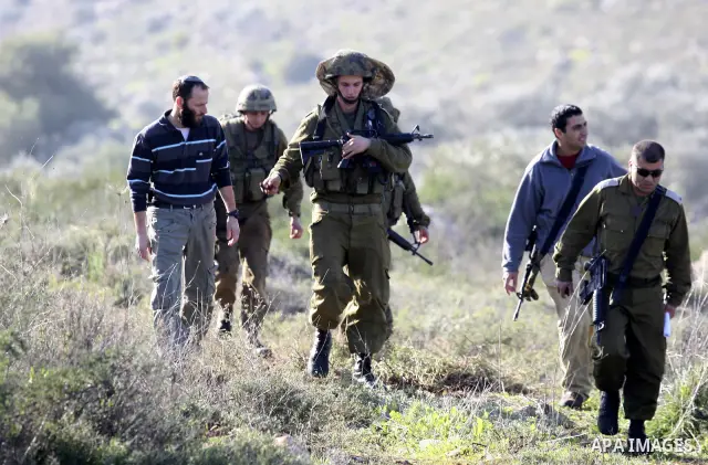 Israeli soldiers stand guards as a bulldozer of the Civil Administration during a demolition in the village of Kufr Qaddum near the Israeli settlement of Kdumim, in the northern West Bank, Sunday, Feb , 05, 2012. Photo b...