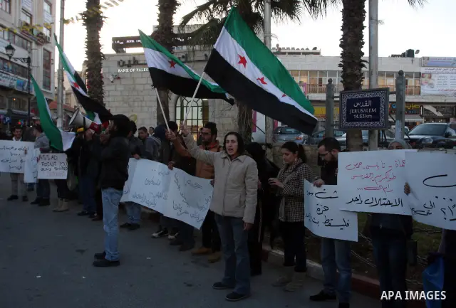 Palestinians hold Syrian flags and signs as they join a demonstration in the West Bank city of Ramallah on Feb 05, 2012. Photo by Issam Rimawi