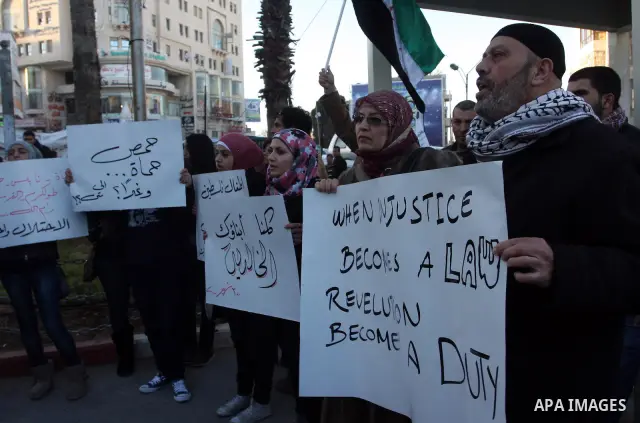 Palestinians hold Syrian flags and signs as they join a demonstration in the West Bank city of Ramallah on Feb 05, 2012. Photo by Issam Rimawi