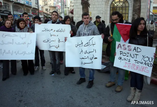 Palestinians hold Syrian flags and signs as they join a demonstration in the West Bank city of Ramallah on Feb 05, 2012. Photo by Issam Rimawi