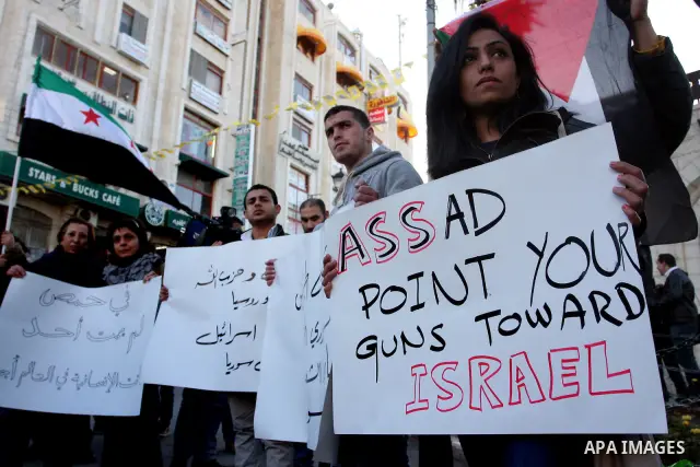 Palestinians hold Syrian flags and signs as they join a demonstration in the West Bank city of Ramallah on Feb 05, 2012. Photo by Issam Rimawi