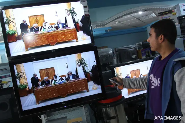 A Palestinian watch a television broadcast of Palestinian President Mahmoud Abbas and Hamas leader Khaled Meshaal in Doha, at an appliance store in Gaza City February 6, 2012. Photo by Mohammed Asad