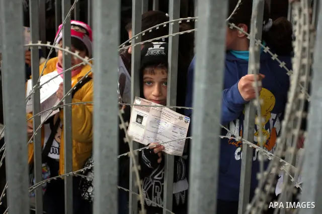 A Palestinian boy holds his permit to enter Israel as he waits at the Qalandia checkpoint between the West Bank city of Ramallah and Jerusalem, Monday, Feb. 6, 2012. Photo by Issam Rimawi