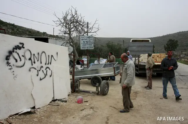 A Palestinian man looks at graffiti sprayed in the West Bank village near Nablus, Feb. 07, 2012. Palestinians say that Jewish extremists had been found on the streets of the village and the man fled, and two Jewish women...