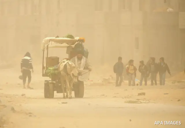 Palestinians walk at a street during cold winds and sand storms in the southern Gaza Strip town of Rafah on February 7, 2012. Photo by Abed Rahim Khatib
